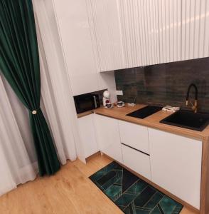 una pequeña cocina con armarios blancos y cortina verde en Apartament Gold Luxury 3, en Baia Mare