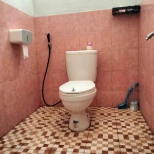 a bathroom with a toilet in a pink tiled wall at Moana Raja Ampat Homestay in Poelau Mansoear