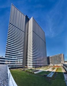 two tall buildings in a city with a grass field at Fraser Place Antasya Istanbul in Istanbul