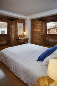 a bedroom with a large white bed with a stone wall at Casa De Janeiro in Janeiro de Cima