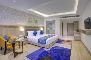 a bedroom with a king sized bed and a table and a chair at Cygnett Inn Airport in Mohāna +37 photos