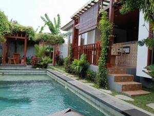 a house with a swimming pool in front of a house at Otila Bali Villa in Uluwatu