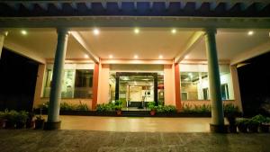 a lobby of a building with columns and plants at Sakthi River Resort in Pollāchi