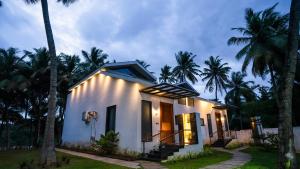 a house with lights on the side of it at Sakthi River Resort in Pollāchi