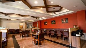 a restaurant with red walls and tables and chairs at Sakthi River Resort in Pollāchi
