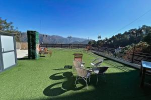 a balcony with chairs and tables on the grass at Hill Crest By Xaria Luxury Homes 2BHK Apartment in Dharampur