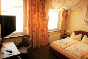 Dormitorio con cama, escritorio y TV en Hotel-Pension Grüne Linde, en Delitzsch