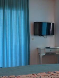 a bedroom with a blue curtain and a tv at Camlikosk Apart Hotel in Bodrum City