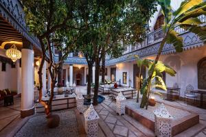 une cour avec des arbres et des canapés dans un bâtiment dans l'établissement Riad Les Jardins d'Henia, à Marrakech