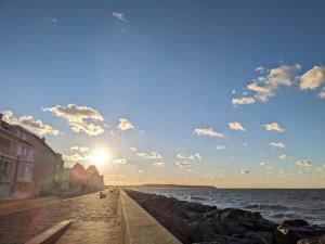 Una vista del océano desde un muelle con la puesta de sol. en seagarden wissant, en Wissant