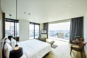 a bedroom with a white bed and large windows at TK Palace Hotel & Convention Bangkok in Bangkok