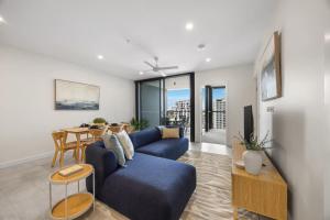 a living room with a blue couch and a table at Rivello Apartments - Free Secure Car Parking in Brisbane