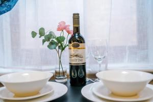 a bottle of wine sitting on a table with two white bowls at Victoria Park Studio 11 - Free Parking, WiFi, Near Town Centre, Free DisneyPlus, Prime & Netflix in Leamington Spa +15 photos