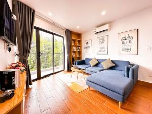 un salon avec un canapé bleu et une télévision dans l'établissement Oikia Westlake Apartment, à Hanoï