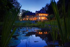 a large house with a pond in front of it at hideauts hotels Der Rosengarten in Füssen