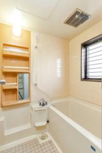 a bathroom with a tub and a sink and a mirror at en stay001 in Osaka