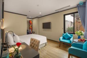ハノイにあるSolare De Monte Hotel & Spaのベッド、テーブル、椅子が備わるホテルルームです。