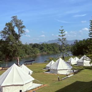 a group of tents in a field next to a river at Rivendale in Ban Gaeng Cho