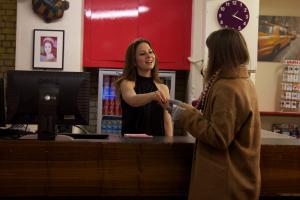 deux femmes qui serrent la main sur un registre de caisse dans l'établissement Dover Castle Hostel, à Londres