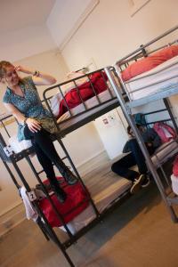 une femme assise au-dessus d'un lit superposé dans l'établissement Dover Castle Hostel, à Londres