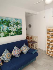 a blue couch in a living room with a painting at fantástico apartamento chipiona in Chipiona
