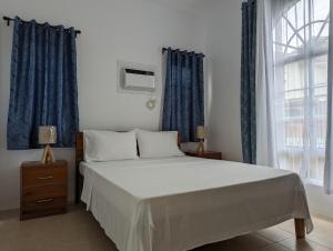 a bedroom with a large bed with blue curtains at Balay Hermosa in Dauis +23 photos