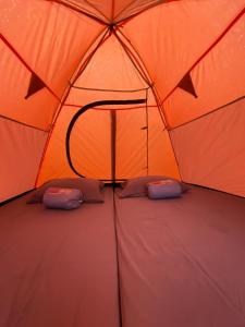 an orange tent with two pillows on top of it at Kebun Teduh Sukaharja Cijeruk Bogor in Palasari +43 photos