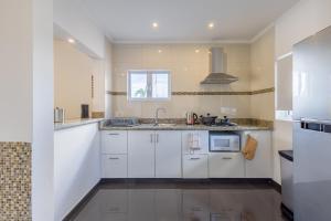 ウィレムスタッドにあるGrey Apartmentsの白いキャビネットとシンクのあるキッチン +2枚の写真