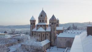 an old church with snow on the roof at Gastflügel der Abtei Maria Laach in Glees