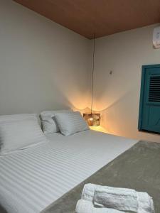 a bedroom with a large white bed with a blue door at Maison Plage Atins - Casa de Praia e Jacuzzi in Atins
