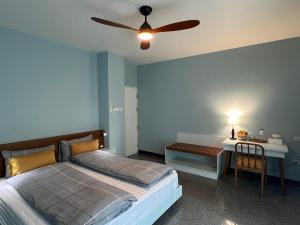 a bedroom with a bed and a desk and a ceiling fan at Dusita Residence in Bangkok