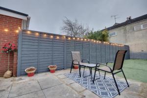 a patio with chairs and a fence with lights at Holiday Home in Central Southsea in Portsmouth