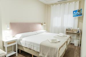 a white bedroom with a bed and a window at Pensión María Castaña in Puebla del Brollón