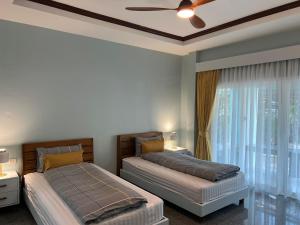 a bedroom with two beds and a ceiling fan at Dusita Residence in Bangkok