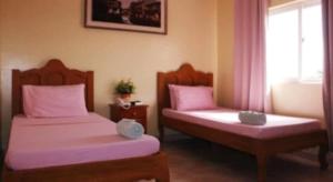 a room with two beds with pink sheets and a window at Rodolfo Royale Hotel in Puerto Princesa City
