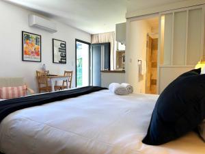 a large white bed in a room with a kitchen at Studio Alba - Confort moderne - Terrasse - Parking gratuit - Non fumeur in Fumel