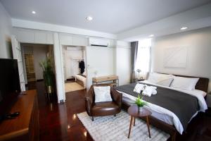 a bedroom with a large bed and a chair at Spacious 4-Bedroom Oasis in the Heart of Sukhumvit in Bangkok