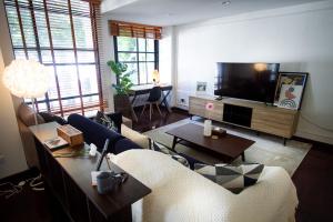 a living room with a couch and a tv at Spacious 4-Bedroom Oasis in the Heart of Sukhumvit in Bangkok