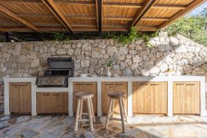 an outdoor kitchen with two stools and a stove at Aella Exclusive Residences Lefkada in Mikros Gialos