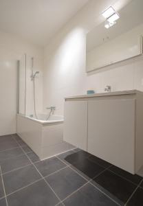 a bathroom with a shower and a sink and a tub at Duinhof VI 6 in Cadzand