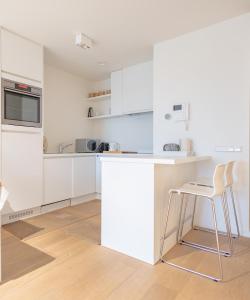 a white kitchen with a counter and a stool at Duinhof VI 6 in Cadzand
