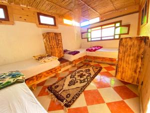 een kamer met 2 bedden en een tapijt op de vloer bij 33 Taghazout in Taghazout