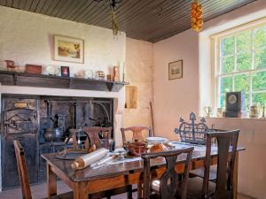 a dining room with a table and a fireplace at Pass the Keys Beautiful Cottage in Historical Robert Burns Farm in Dumfries