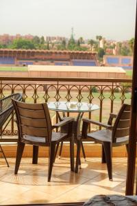 einen Tisch und Stühle auf einem Balkon mit einem Baseballfeld in der Unterkunft Cosy cocon au coeur de Gueliz-Parking gratuit in Marrakesch