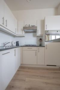 a white kitchen with white cabinets and stainless steel appliances at Duinhof I 15 in Cadzand +2 photos