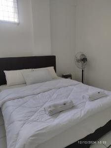 Una cama blanca con dos toallas encima. en TDT STAY-Homestay, en Keningau