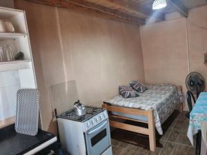 a small room with a stove and a bed at Macrigaluma Luna solo con seña in Barra del Chuy +6 photos