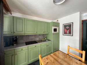 a kitchen with green cabinets and a wooden floor at Chalet du Galibier Valloire in Valloire