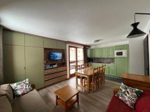 a living room with green cabinets and a table and a kitchen at Chalet du Galibier Valloire in Valloire