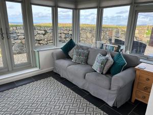 a living room with a couch in front of windows at Lower Trowan Cottage in Sharnbrook